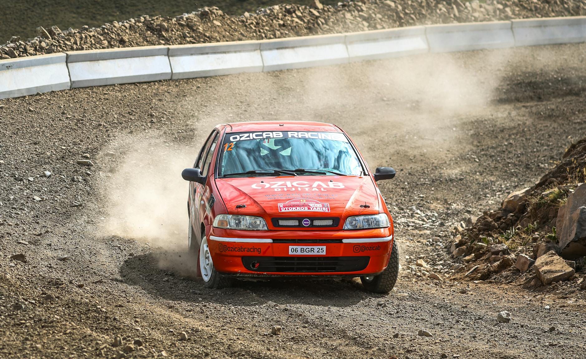 Fiat Palio pędzący po szutrowym odcinku specjalnym w kurzu