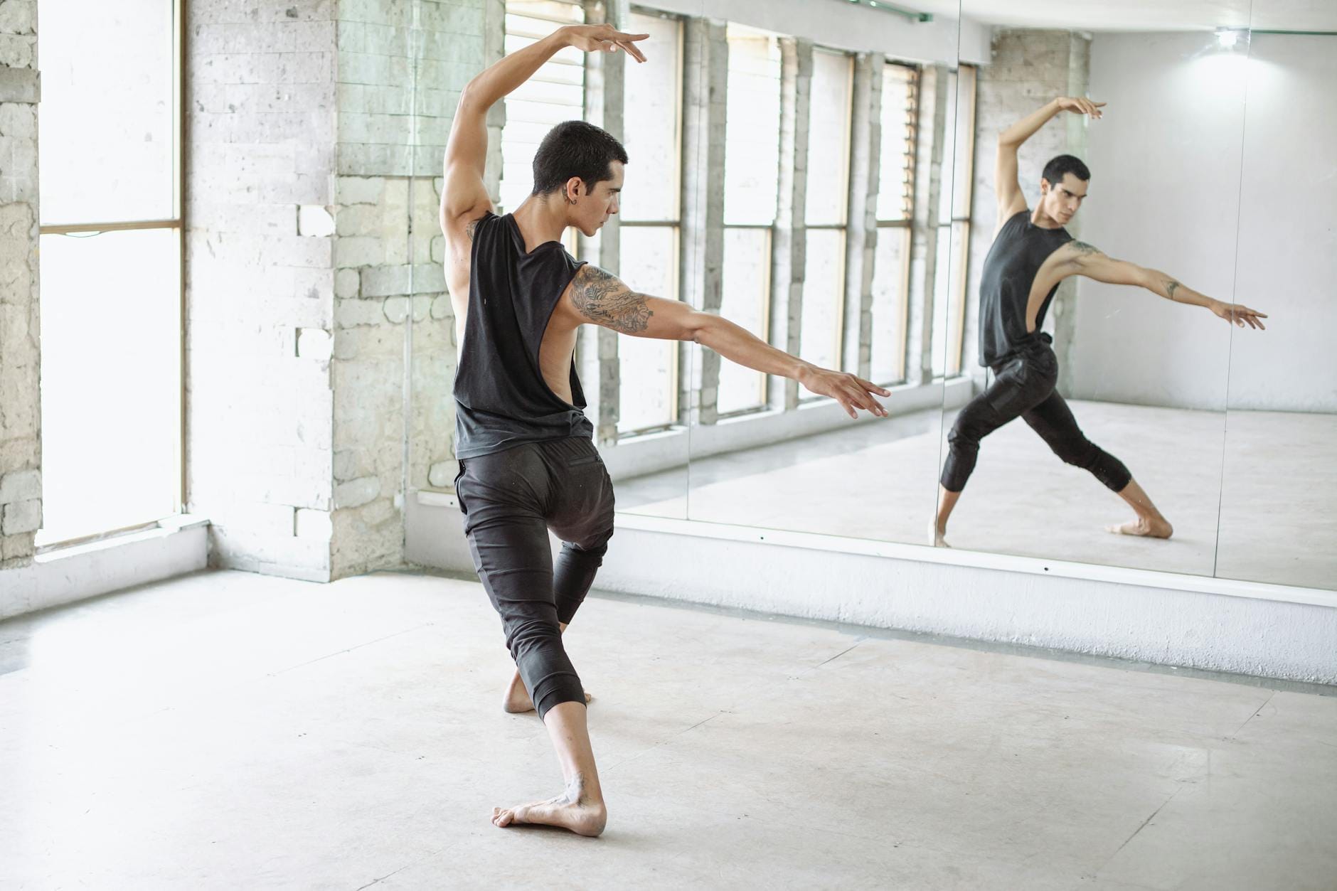 Tancerz baletowy ćwiczy układ przed lustrem w jasnej sali tanecznej