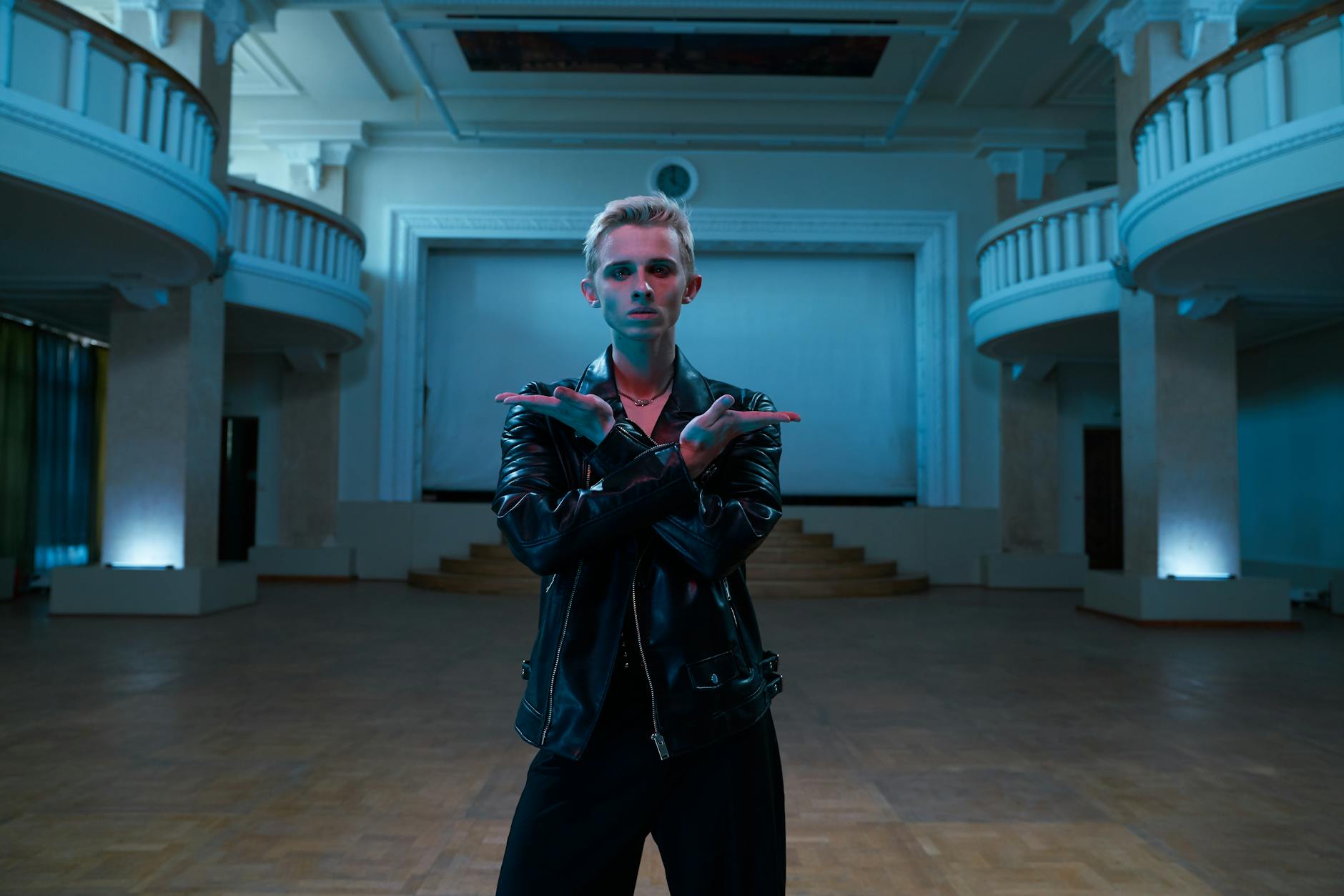 Tancerz współczesny w skórzanej kurtce pozuje w zabytkowej sali balowej