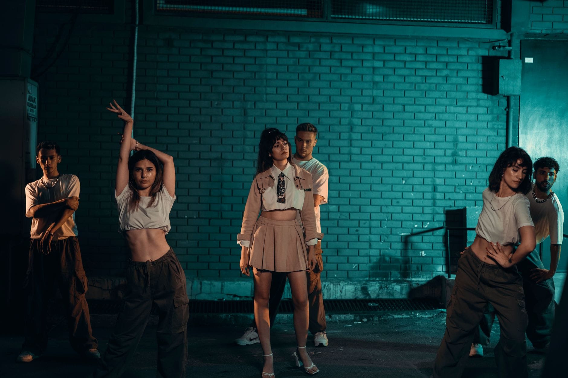 Grupa tancerzy street dance tańczy energicznie nocą przy ceglanej ścianie