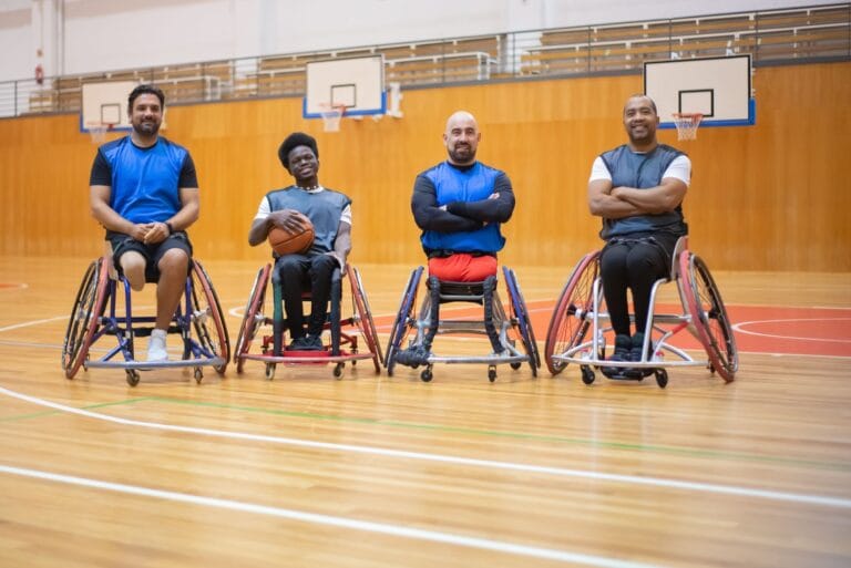 Czterech koszykarzy na wózkach pozuje na hali sportowej